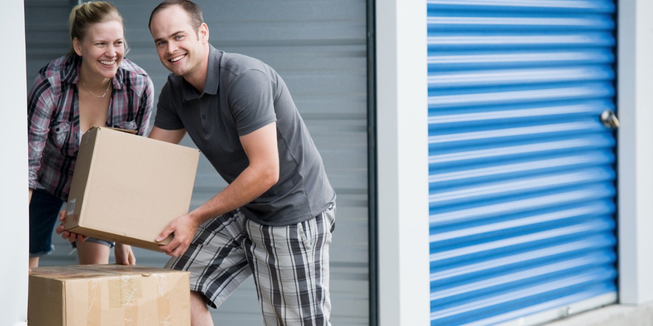 A couple carrying moving boxes into their Butters storage unit